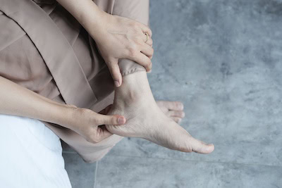 Person holding their bare foot and ankle to check for neuropathy pain
