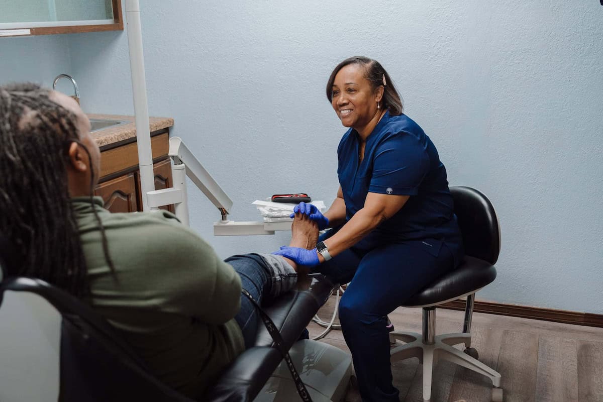 Smiling nurse talking with a patient about neuropathy foot care in an exam room